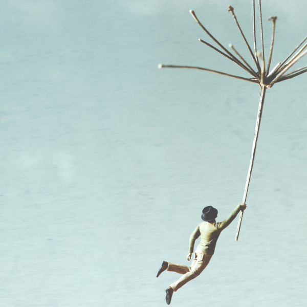 a man flying through the sky holing onto a broken umbrella