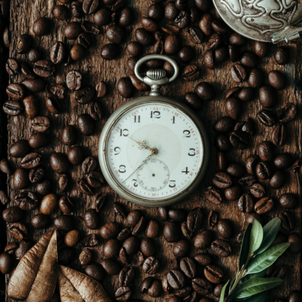 a pocket watch surrounded by coffee beans
