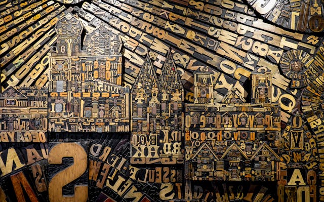 An image of a cityscape composed of carved wood letters and numbers.